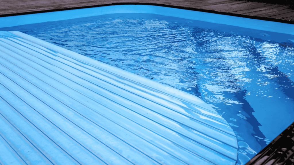 A blue colored pool is being covered by an automatic cover.