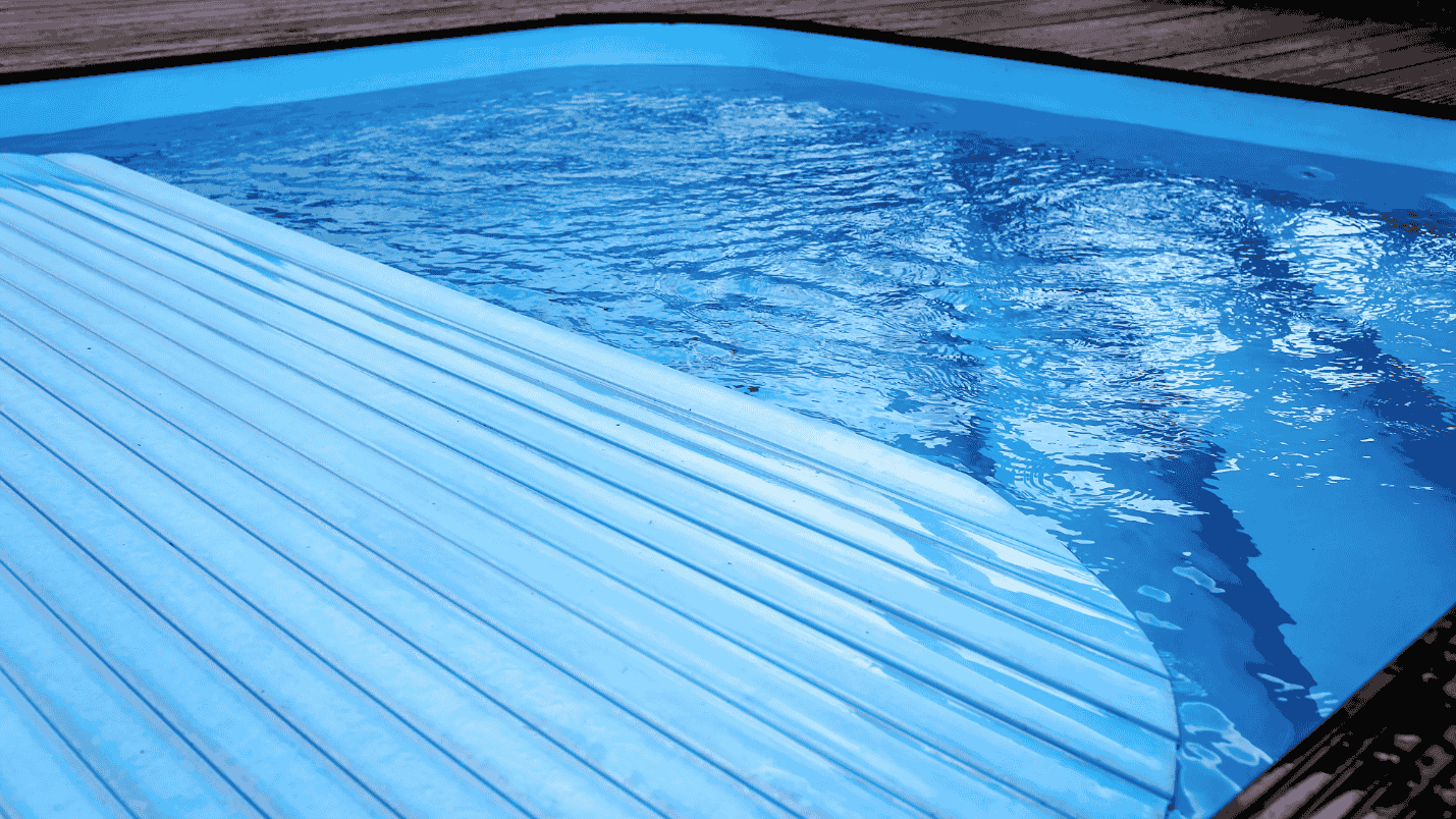 A blue colored pool is being covered by an automatic cover.