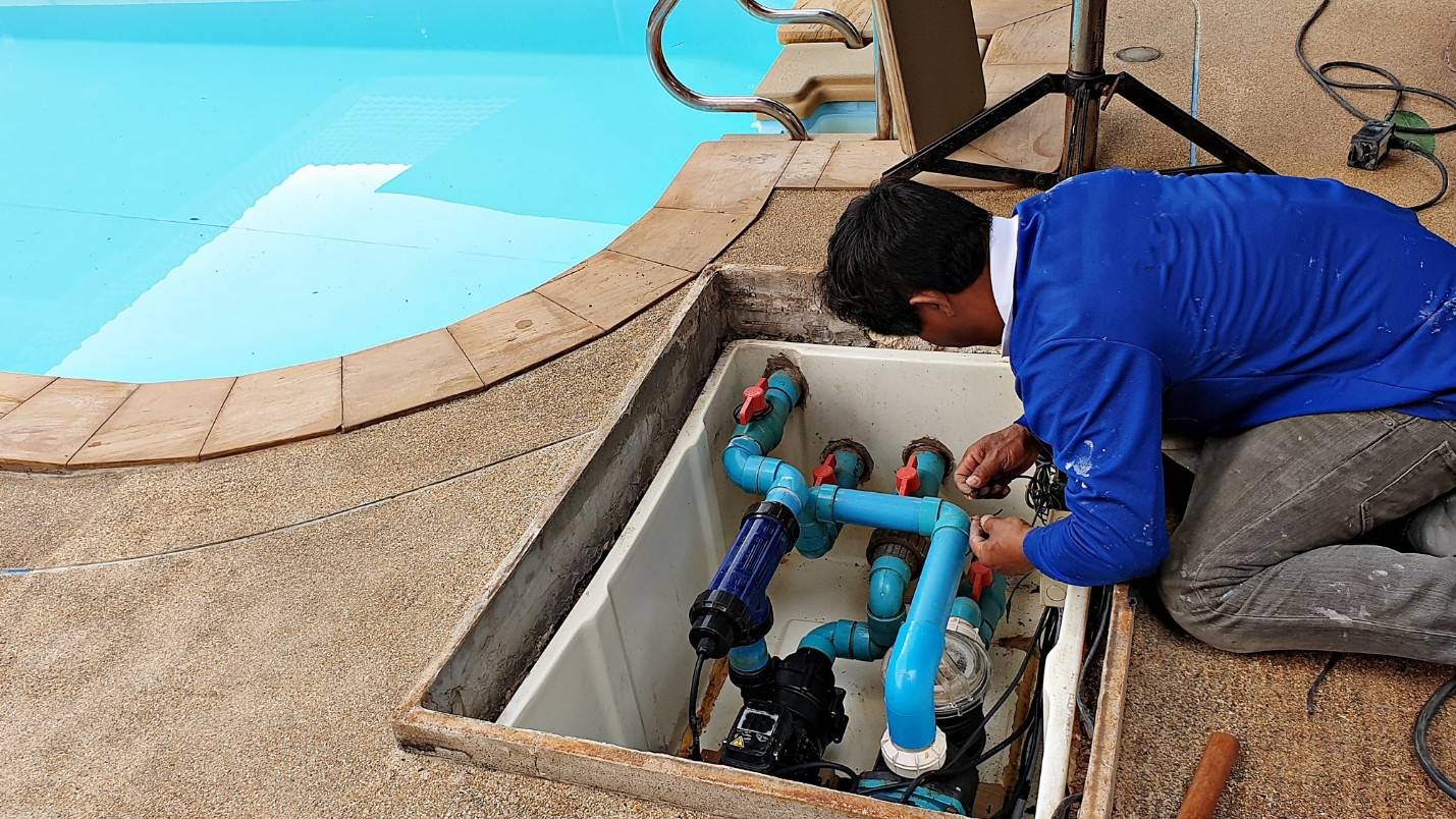 A pool contractor works on a broken pool pump.