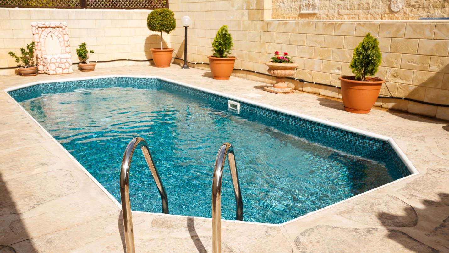 A plunge pool with teal tiles in a small backyard space.