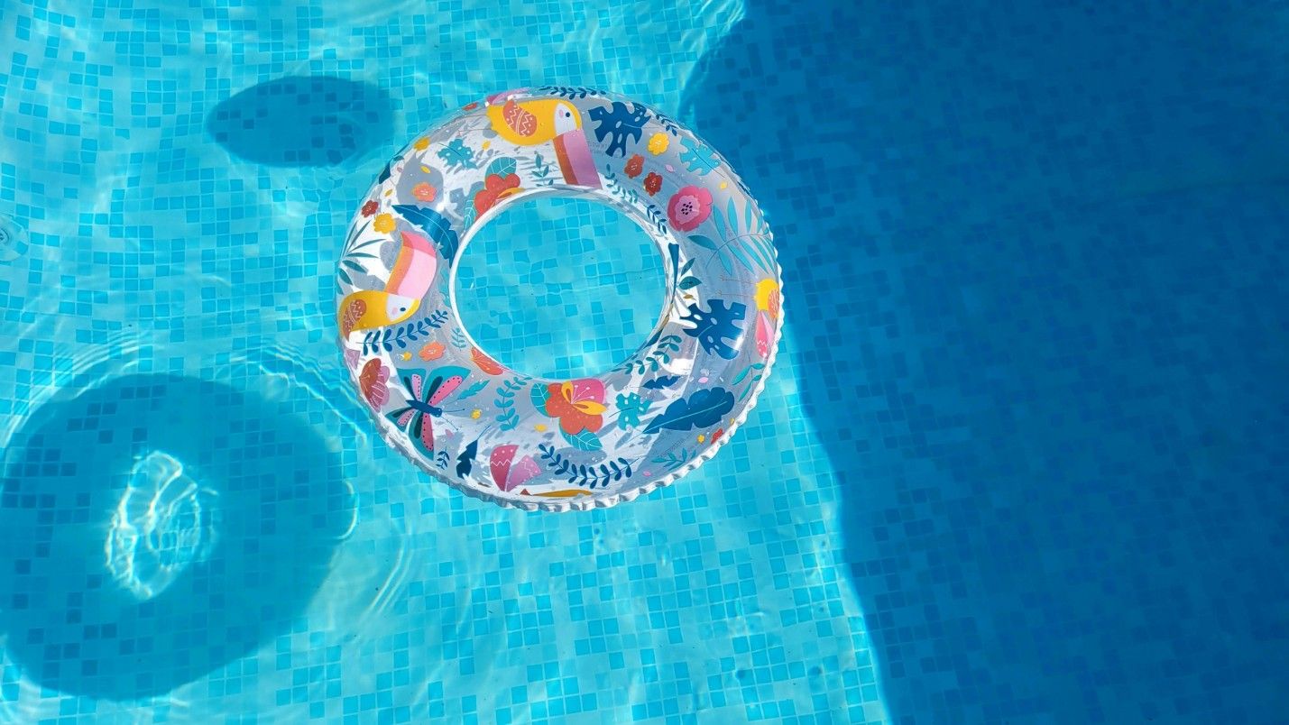 A clear water pool with light blue tiles and a ring floaty.