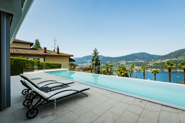 Two lounge chairs overlooking an infinity pool with a view of water and green hills.